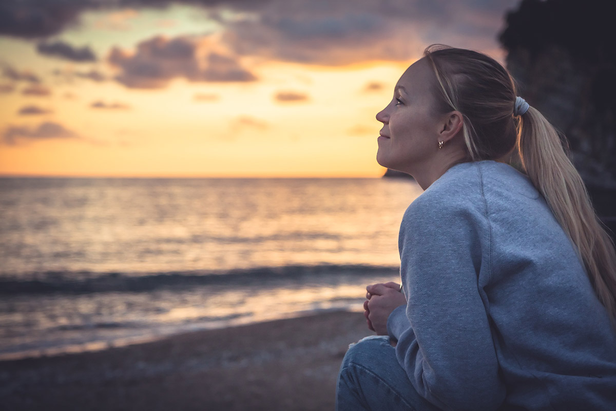 woman watching beach sunset after recovery from drug and alcohol addiction