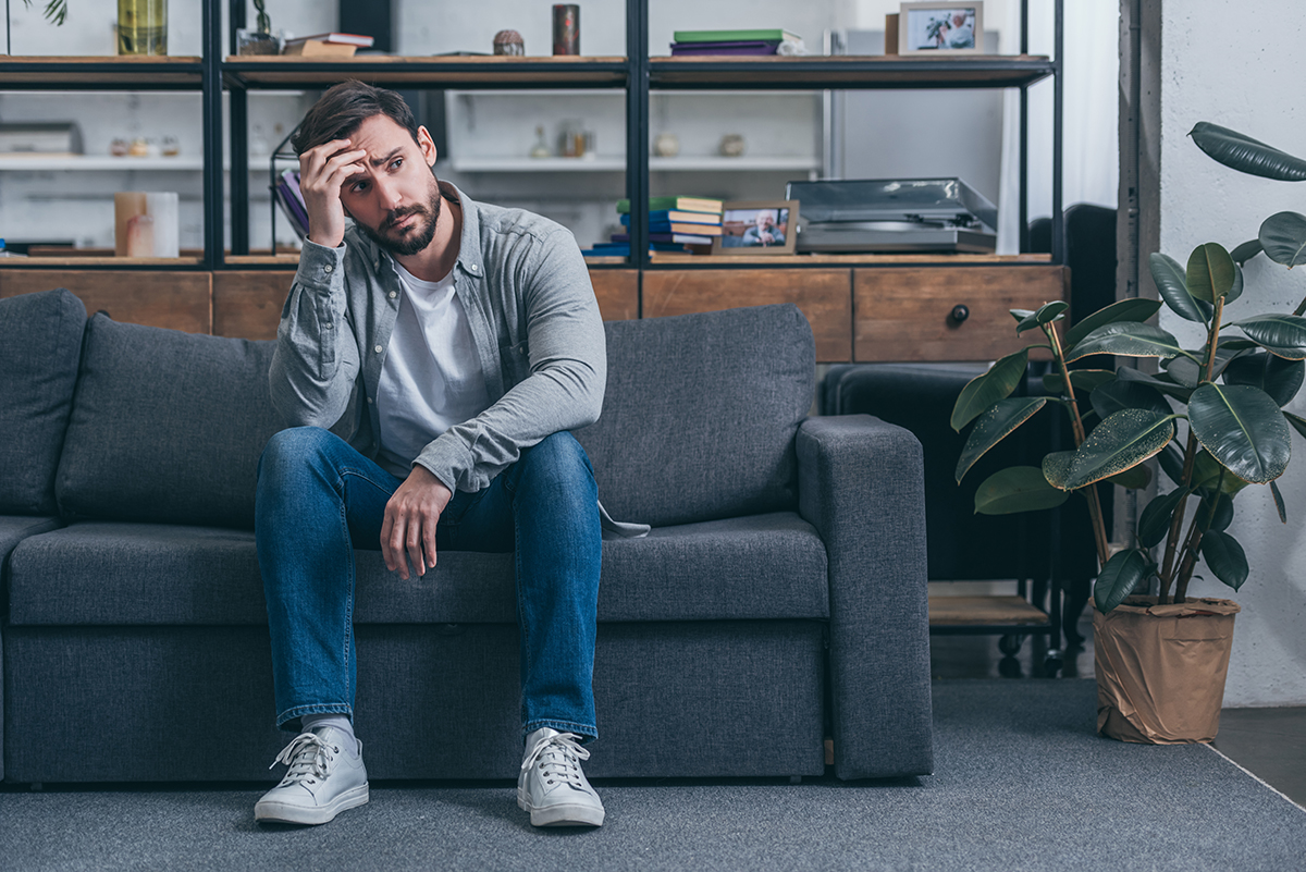 man sits on couch with head in his hand and wonders the difference of crack vs cocaine