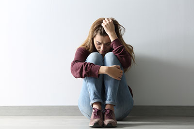 methadone abuse woman sitting on ground against wall head down