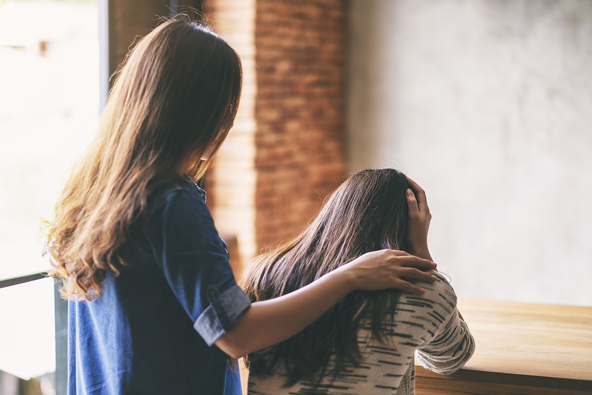 types of addiction, standing woman comforts sitting woman