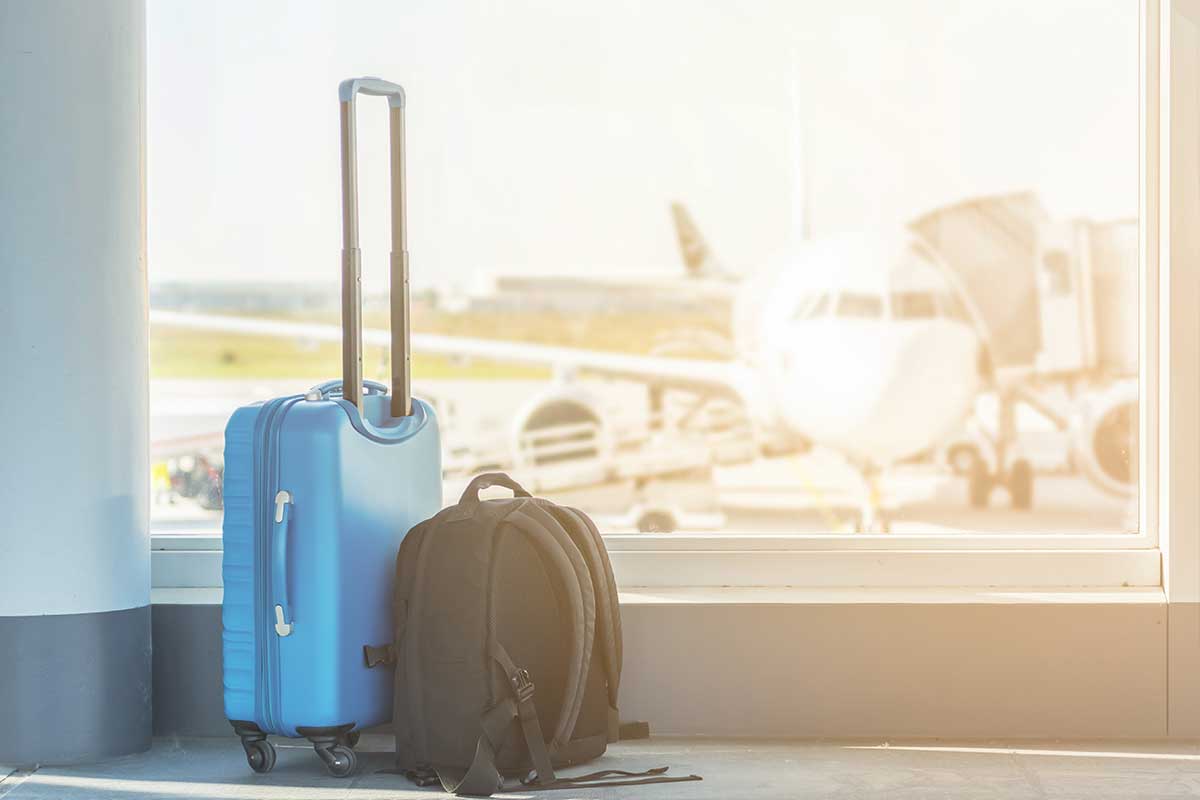 suitcase and backpack in front of a window at an airport